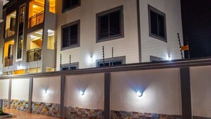 A multi-story hotel with a stone facade and illuminated windows. - Captivating 1-Bed Apartment in Tema, com 25 (Tema, com 25)