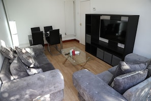 Relax in this stylish living room with a glass-top coffee table, large flat-screen TV, and comfortable sofa.