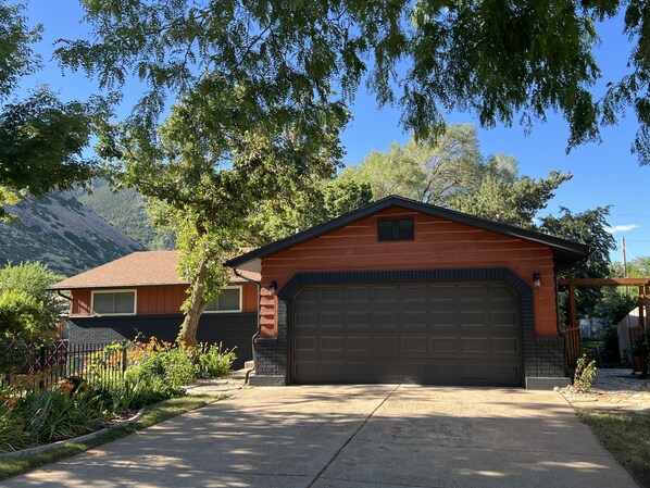 A two-story house with a garage, surrounded by trees and a mountain backdrop. - Mid-Century Modern Gem next to Trails, Ski Resorts and Downtown Ogden (Ogden)