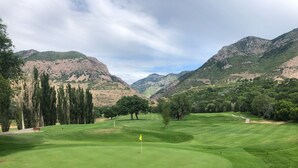 A golf course with a flag, trees, and mountains in the background. - Mid-Century Modern Gem next to Trails, Ski Resorts and Downtown Ogden (Ogden)