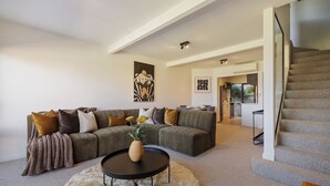 A modern living room with a sectional sofa, a round coffee table, and a staircase. - Mountain Vista 06, Magic Mountain Vista 06 (Queenstown)