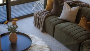 A cozy living room with a sofa, a small round table with a vase of flowers, and a fluffy rug. - Mountain Vista 06, Magic Mountain Vista 06 (Queenstown)
