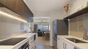 A modern kitchen with a central island, built-in oven, and stainless steel appliances. - Mountain Vista 06, Magic Mountain Vista 06 (Queenstown)