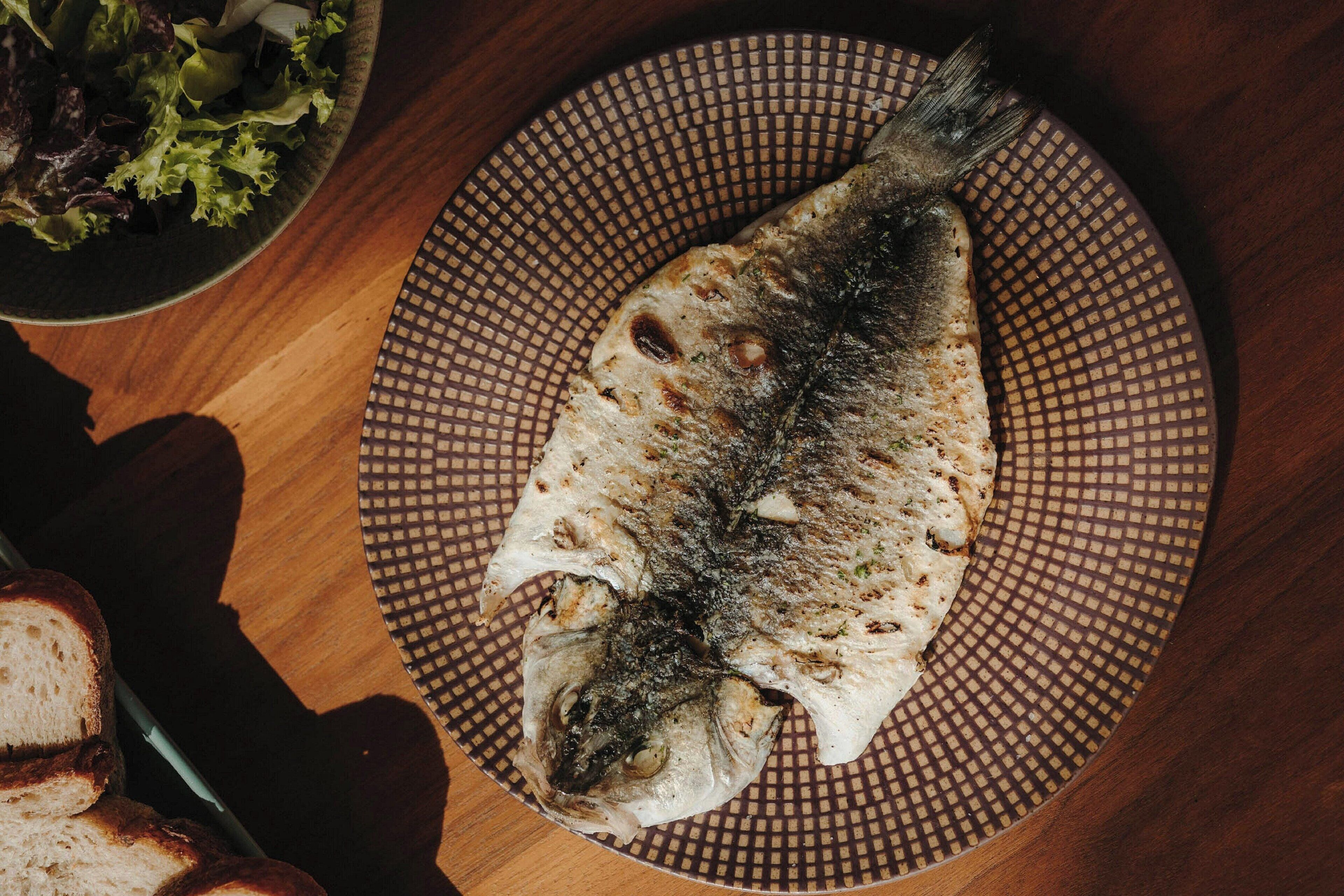 Um peixe num prato com um padrão decorativo.