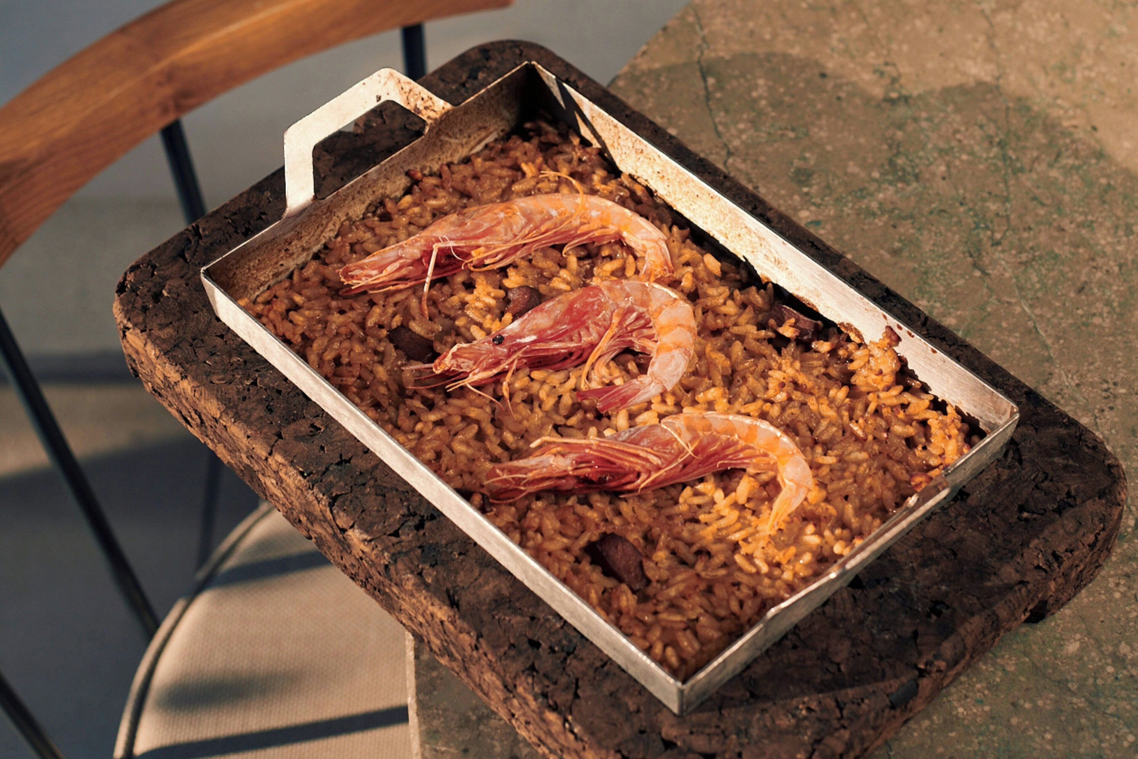 A tray of rice with shrimp on a wooden surface.