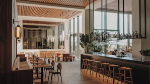 Zona de bar moderna con asientos de madera y una barra que exhibe diversas botellas.