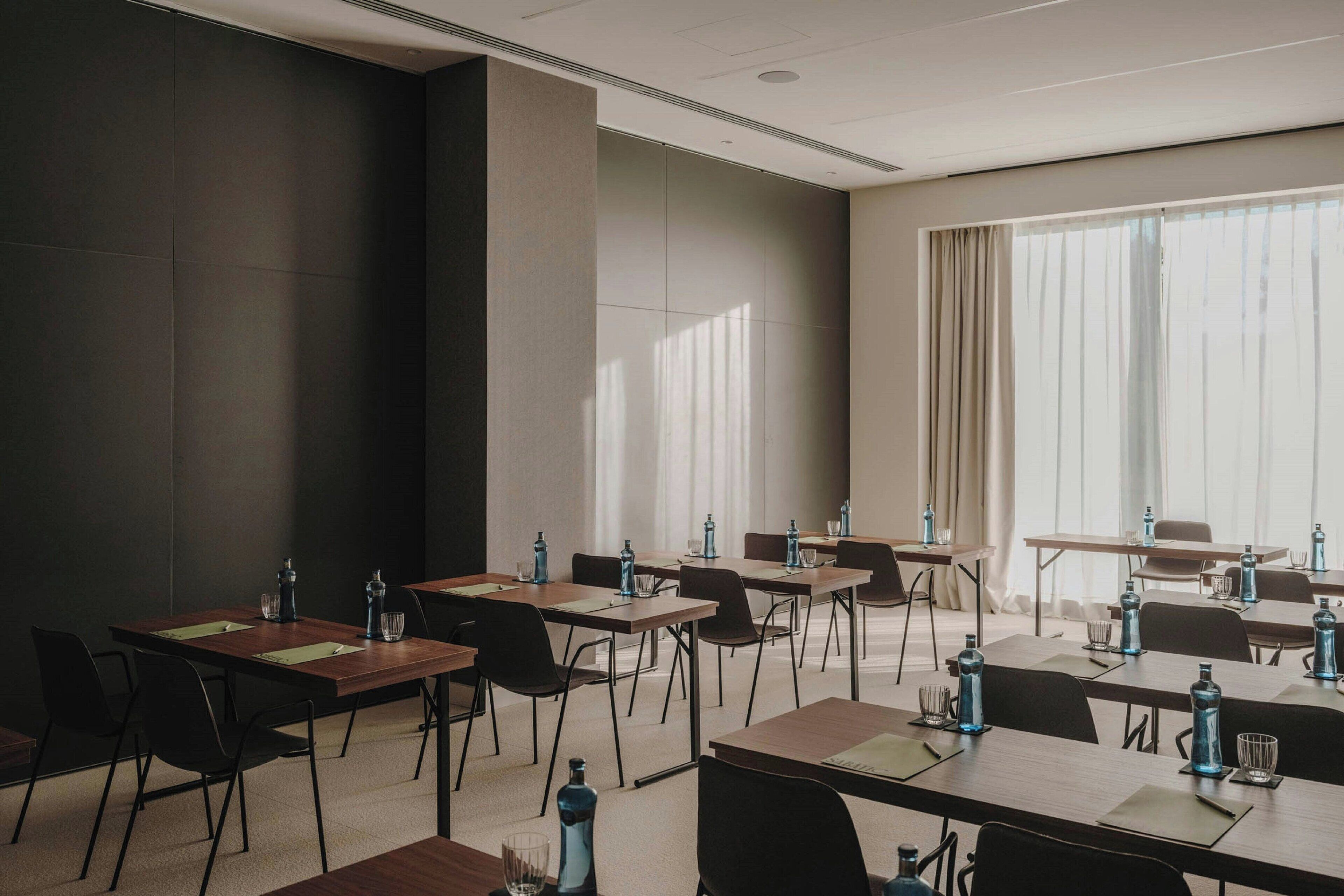 A conference room with multiple tables and chairs, equipped with water bottles and glasses.