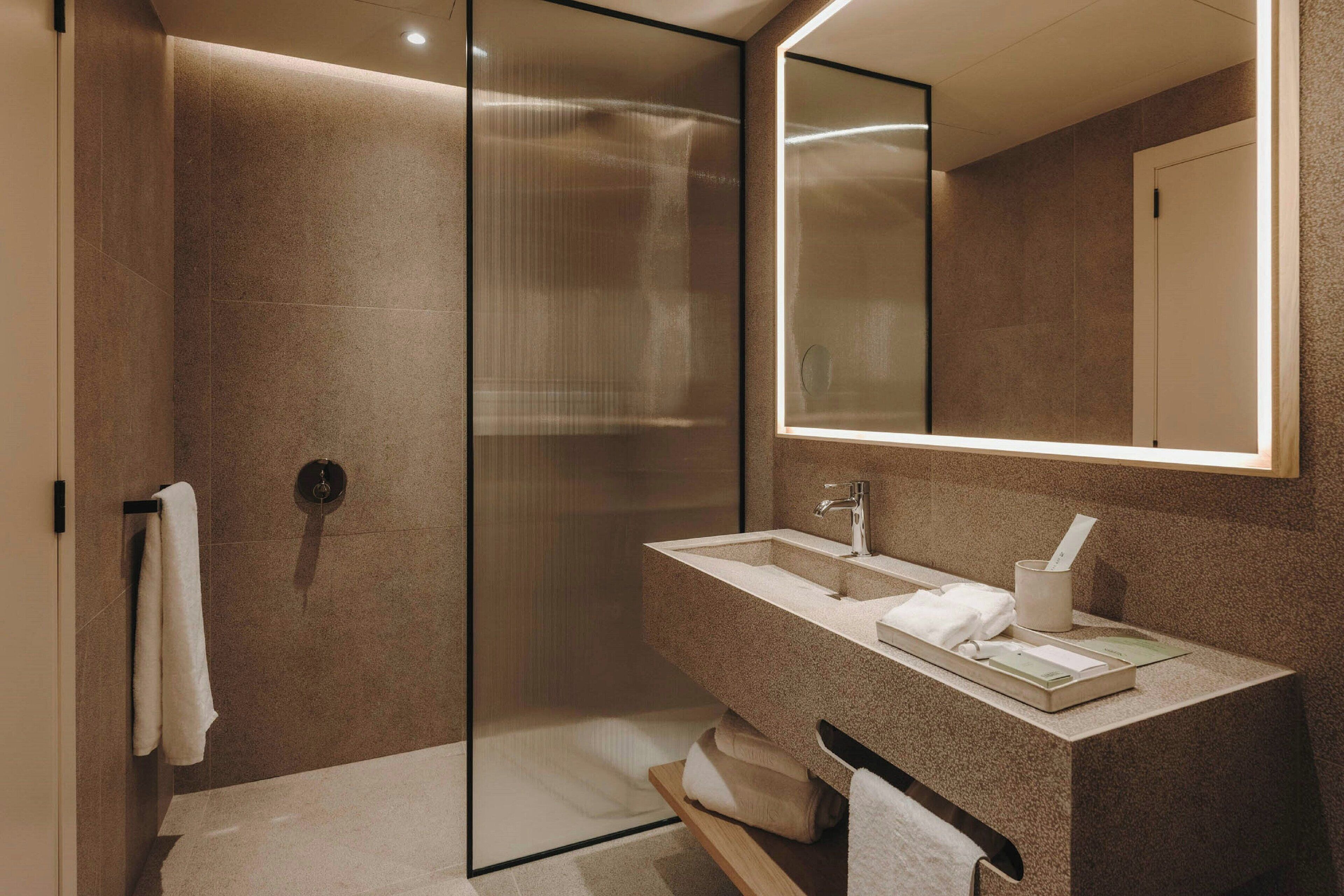 Un baño moderno con cabina de ducha de vidrio, un lavamanos con espejo y un perchero para toallas.