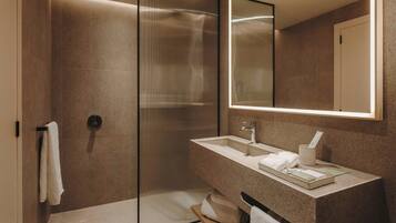 Un baño moderno con cabina de ducha de vidrio, un lavamanos con espejo y un perchero para toallas.