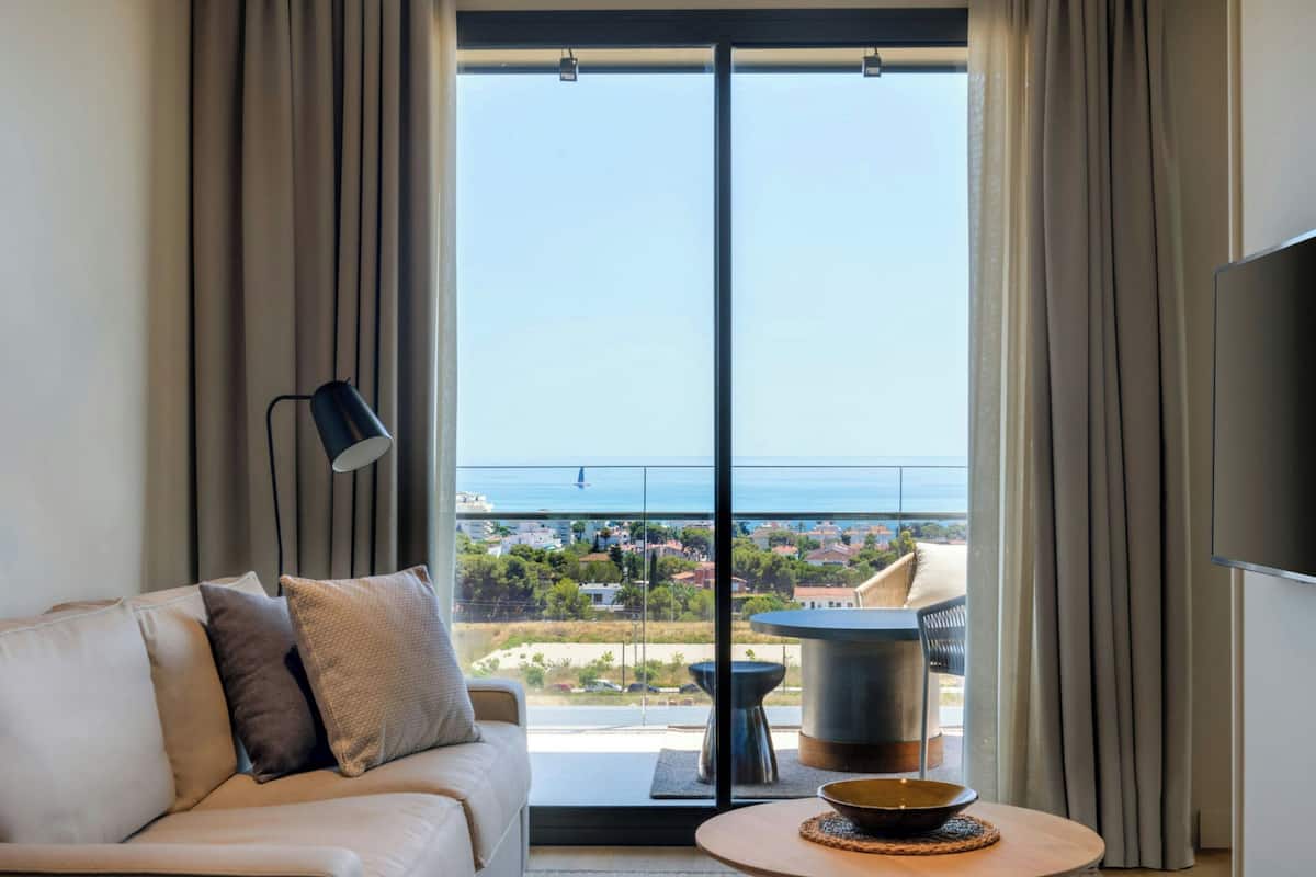 Una sala moderna con un sofá, una mesa de centro y vista al mar a través de amplios ventanales.