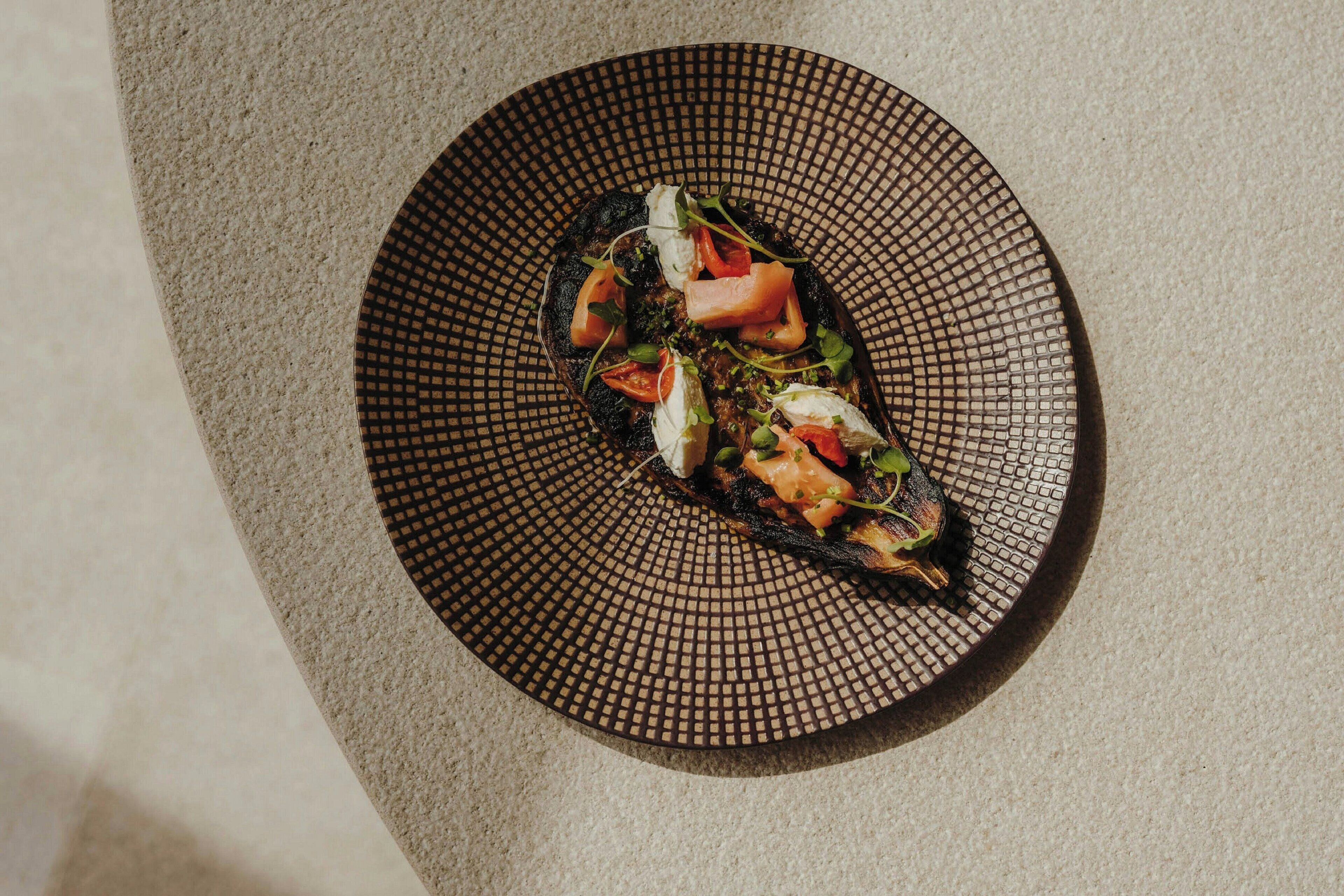 A dish on a textured plate with a geometric pattern.