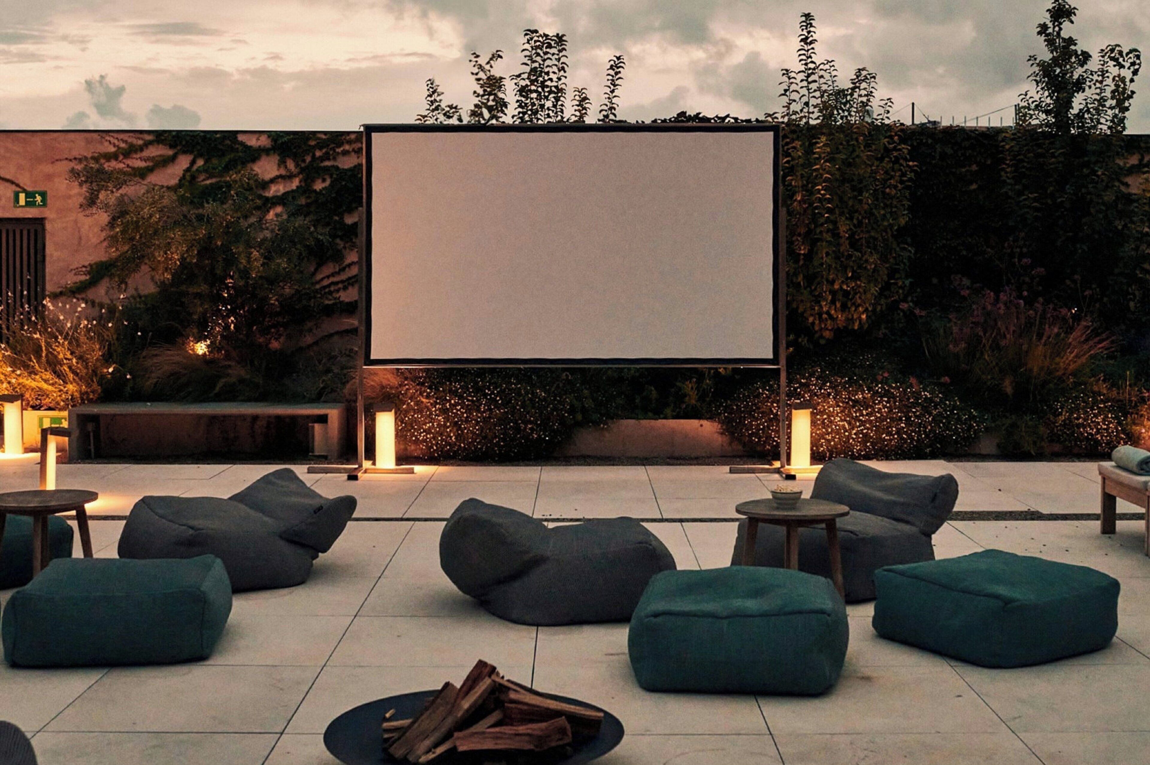 An outdoor seating area with bean bags and a large screen for viewing.
