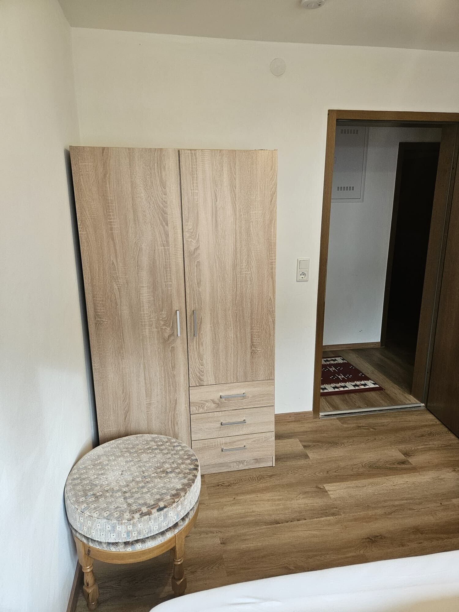 Una camera da letto con un'armadio in legno, un tavolino rotondo e un letto.
