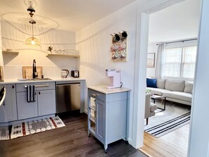 Enjoy a compact kitchenette with sink, coffee maker, and toaster, and relax in the adjacent living area with sofa and coffee table.