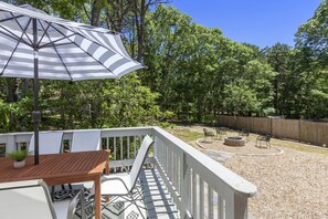 Relax in a serene outdoor space surrounded by lush greenery and a fire pit area.