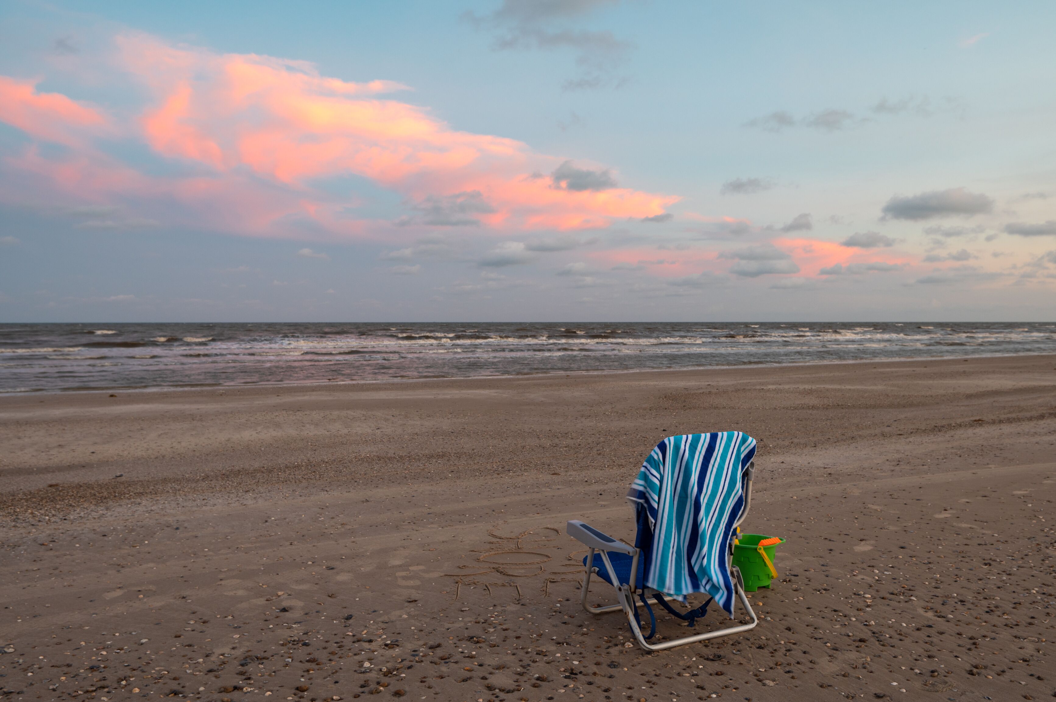 Una playa con una silla y un cubo.