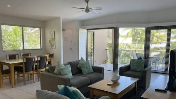 A modern living room with a sofa, armchairs, a coffee table, and a dining area with chairs and a table. - Quiet Noosaville Garden Retreat, Pool, Walk to River & Dining (Noosaville)