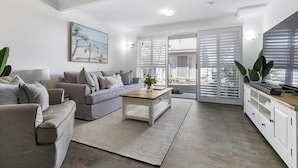A modern living room with a grey sofa, a wooden coffee table, and a white cabinet. - Experience the laid-back Noosa lifestyle! (Noosa)