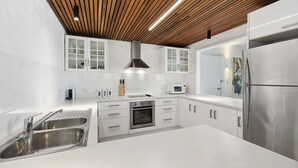 Una cocina moderna con muebles blancos, electrodomésticos de acero inoxidable y techo de madera.