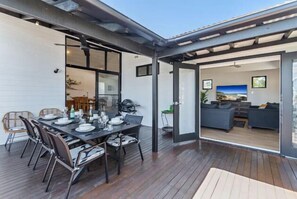 An outdoor dining area with a table set for six, surrounded by chairs. - Stunning Coastal Home! The Perfect Family Getaway (Noosa)