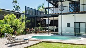 Une maison moderne dotée d’une piscine, d’un espace salon extérieur et d’une végétation luxuriante.