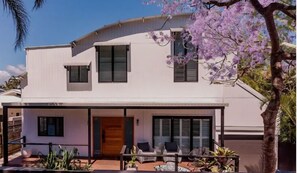 A modern two-story house with a covered patio, large windows, and a well-maintained garden. - Stunning Coastal Home! The Perfect Family Getaway (Noosa)