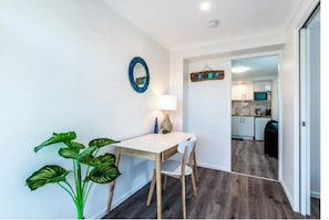 Un espace de vie compact comprenant un coin repas, une petite cuisine et un couloir menant à la salle de bain.