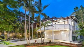 Una casa moderna de dos pisos con un porche cubierto y un jardín cuidado.