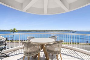 A balcony with a table and chairs, overlooking a body of water with boats. - Panoramic River & Ocean Views - Penthouse -Rooftop (Noosa)