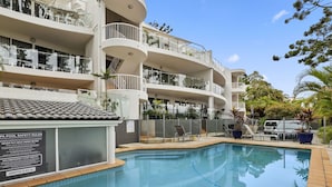A modern building with a swimming pool, multiple balconies, and outdoor seating. - Light, bright and airy with breathtaking views of Noosa Heads! (Noosa)
