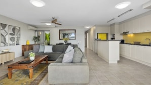 A modern living room with a sofa, coffee table, and a dining area. - Light, bright and airy with breathtaking views of Noosa Heads! (Noosa)