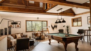 Un salon spacieux équipé d’une table de billard, d’un canapé et d’un bureau.