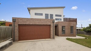 A modern two-story house with a garage, brick exterior, and a small attached structure.