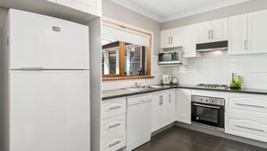 Una cocina moderna con armarios blancos, microondas integrado, estufa a gas y lavavajillas.