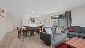 Un salon moderne avec un canapé gris, une table basse en bois et un coin repas comprenant une table et des chaises en bois.