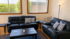 Une pièce avec deux canapés en cuir noir, une petite table et un lampadaire.