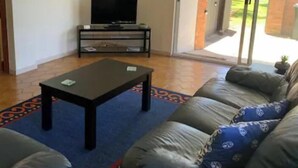 A living room with a sofa, a coffee table, and a television on a stand.
