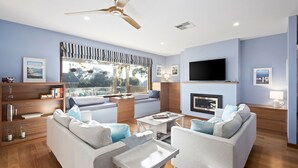 A modern living room with a fireplace, comfortable seating, a flat-screen TV, and a large window with a view.