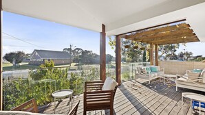 A covered outdoor deck with a view of a house and greenery.