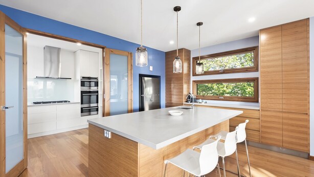 A modern kitchen with a large island, stainless steel appliances, and wooden cabinetry.