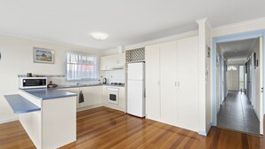 Une cuisine moderne avec des meubles blancs, un plan de travail bleu, un four à micro-ondes, une cuisinière et un réfrigérateur.