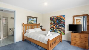 Une chambre à coucher avec un lit en bois, un tableau, une télévision et un miroir.