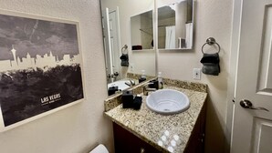 Ein Badezimmer mit Waschbecken, Spiegel und einem Stadtlandschaft-Poster an der Wand.