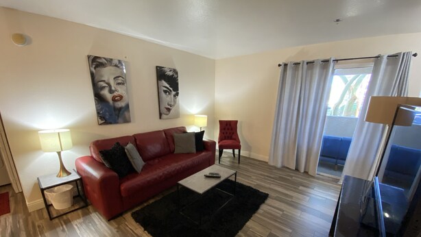 Ein Wohnzimmer mit einem roten Sofa, einem schwarzen Teppich und zwei Bildern an der Wand.