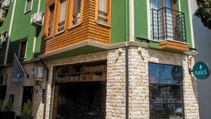 Un edificio de varios pisos con fachada verde, marcos de madera en las ventanas y base de piedra.
