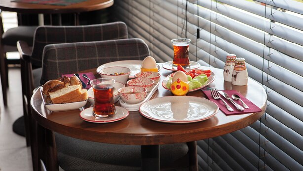 Una mesa de comedor con platos, tazones, cubiertos y una taza de té.