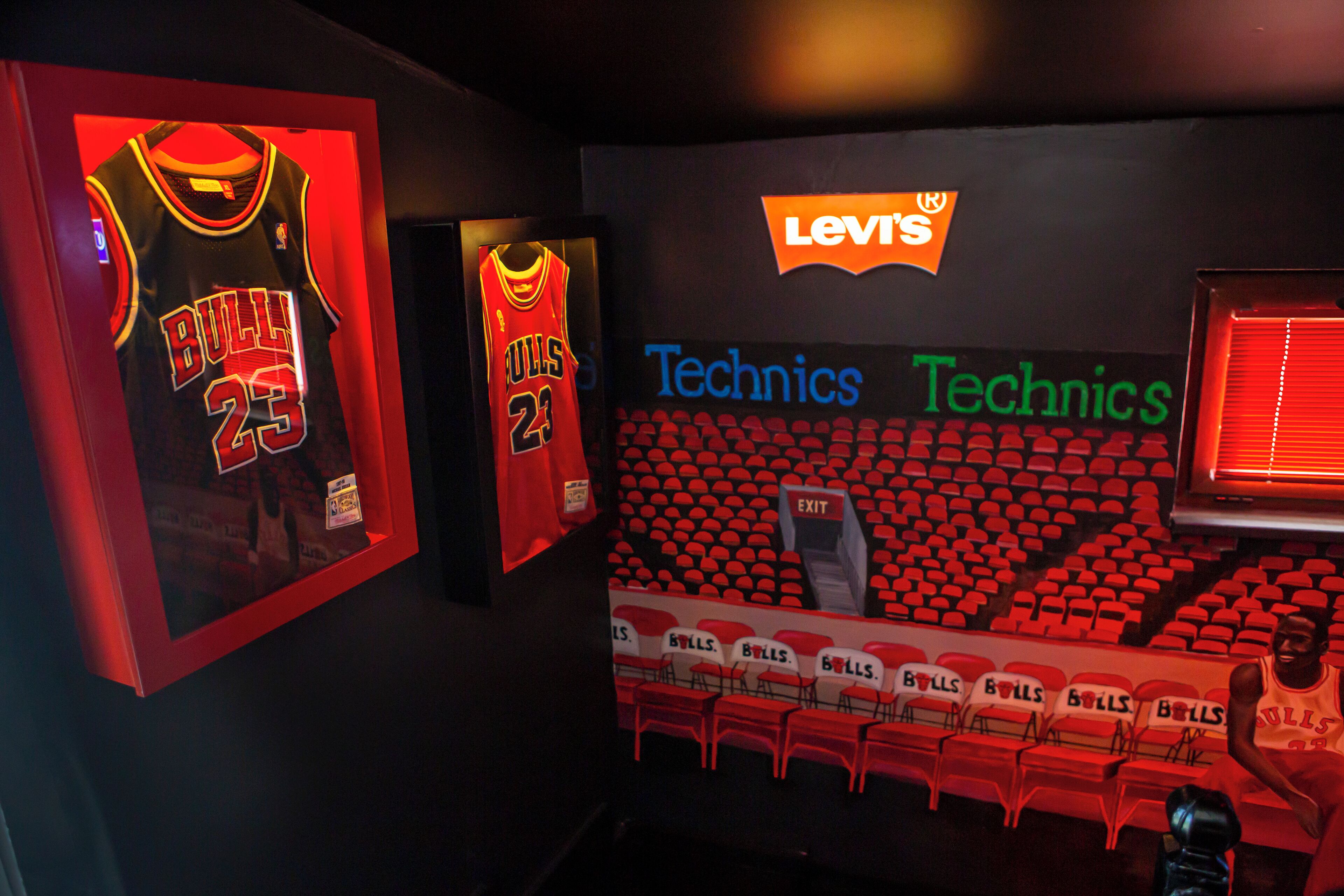 Exhibición con temática deportiva que incluye camisetas enmarcadas y una zona de estar identificada como "Technics".