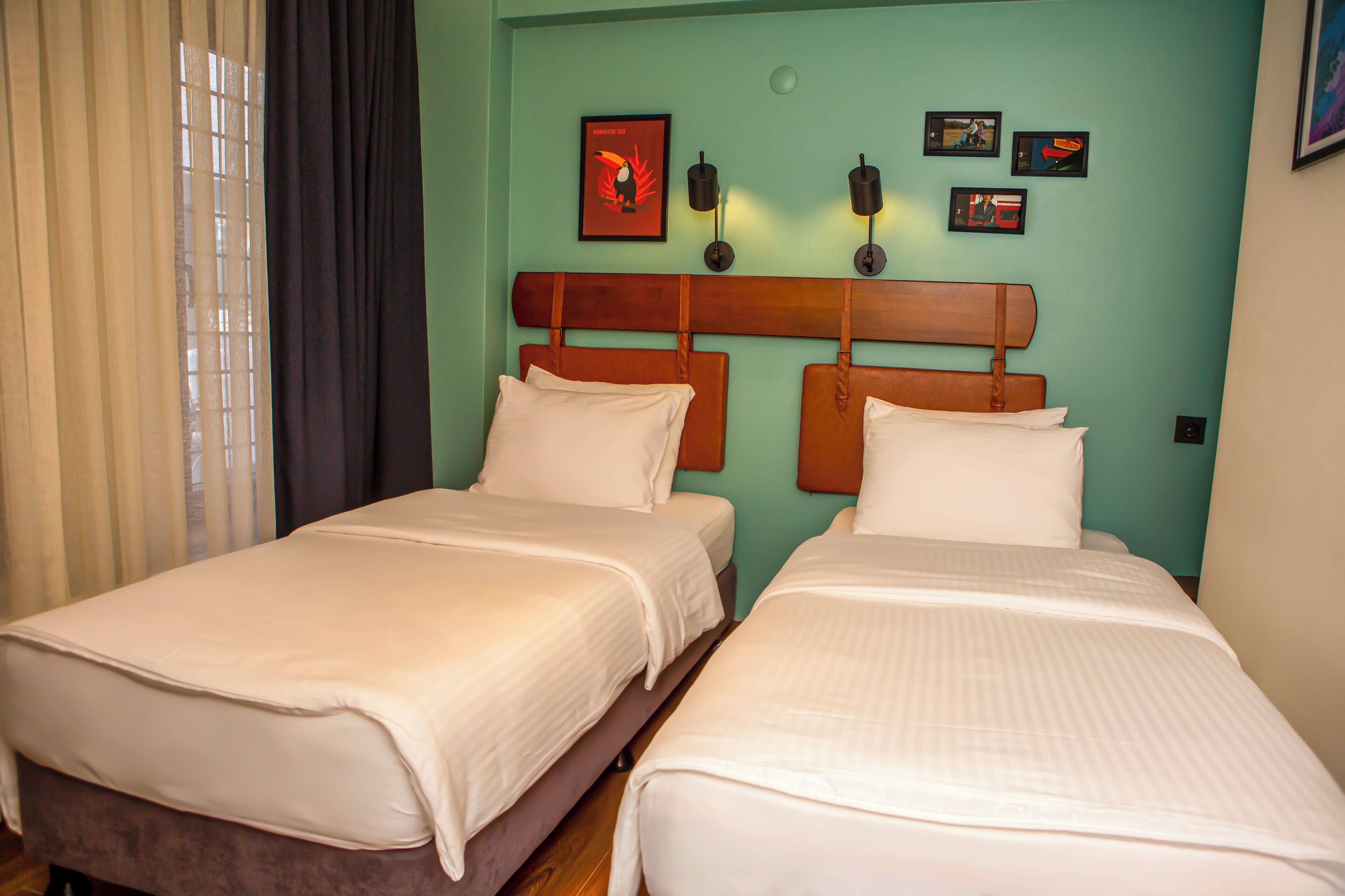 A hotel room with two beds, a wooden headboard, and a teal wall.
