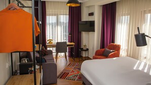 Una habitación de hotel con cama, escritorio, silla y televisor.