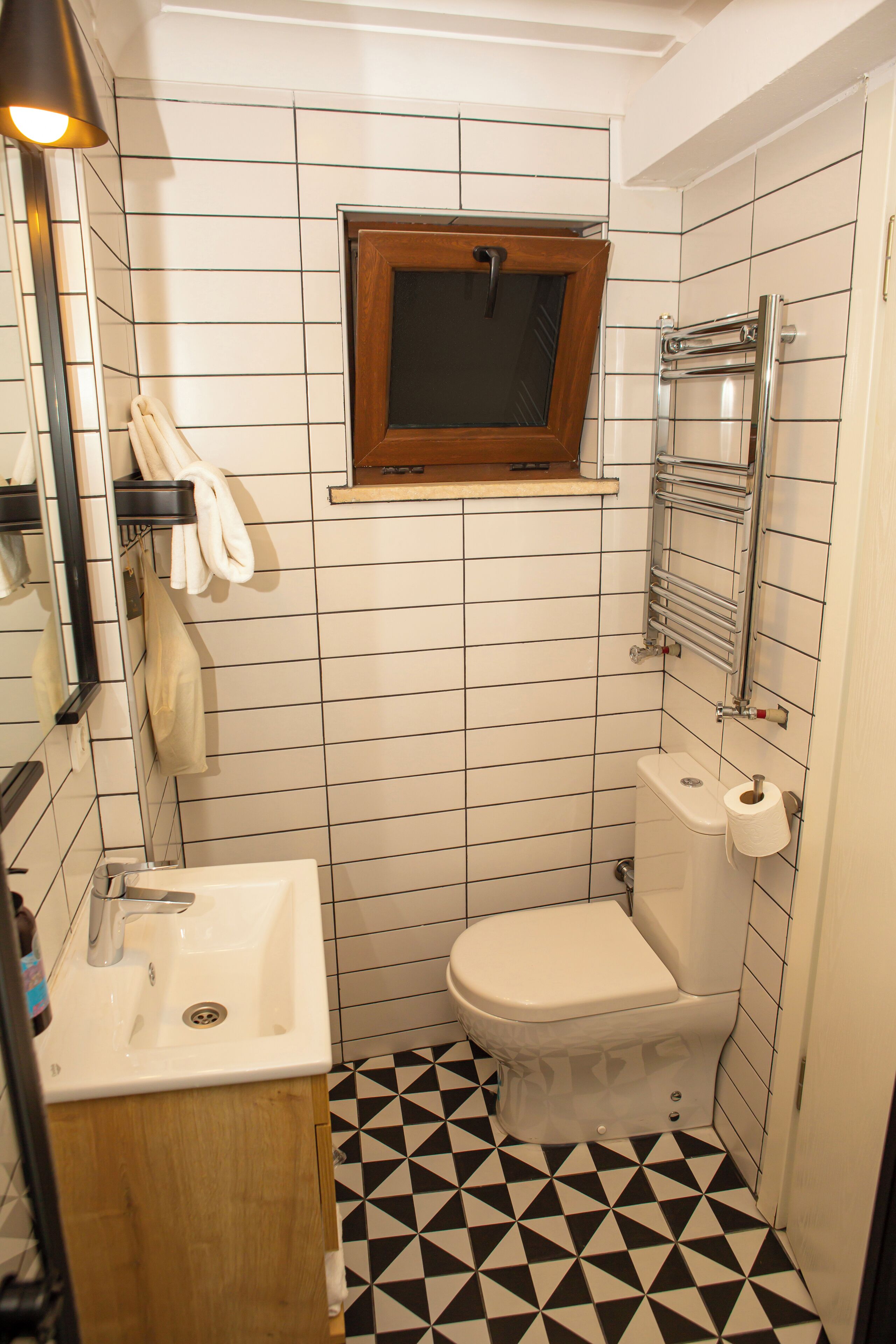 Une petite salle de bain avec un lavabo, des toilettes et une fenêtre située au-dessus des toilettes.